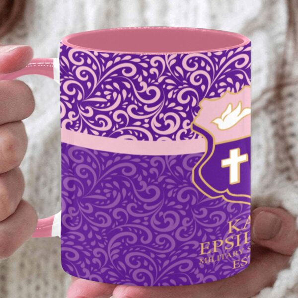 Purple floral mug with emblem held in hand.