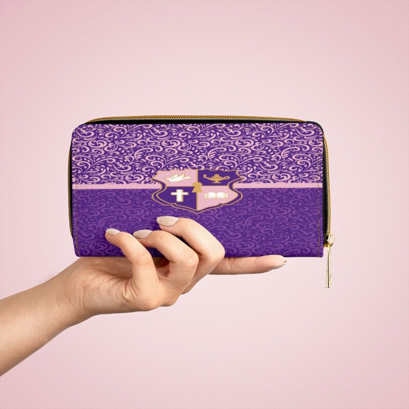 Hand holding purple patterned pouch on pink background.